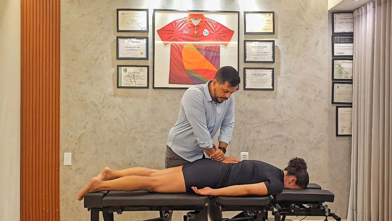 Dr. Pedro Rosário com as mãos na região lombar de paciente deitada de bruços na maca, aplicando técnica manual